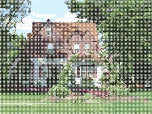 A picturesque scene of a cottage surrounded by foliage and blossoms. A beautiful landscape needlepoint.