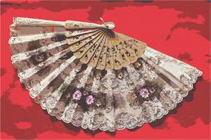 A delicate lace floral fan resting on red fabric